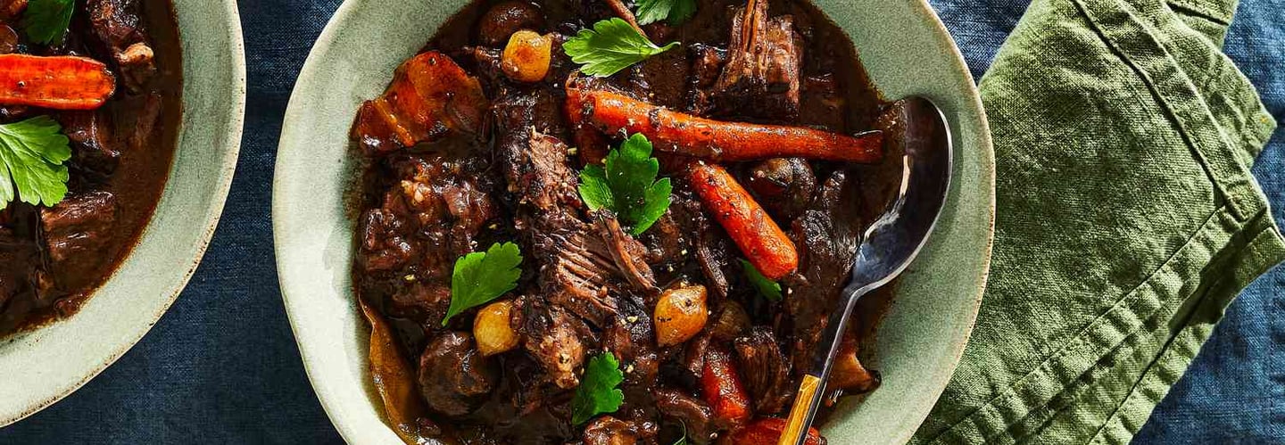 Hearty beef stew with carrots and potatoes simmering in Dutch oven.
