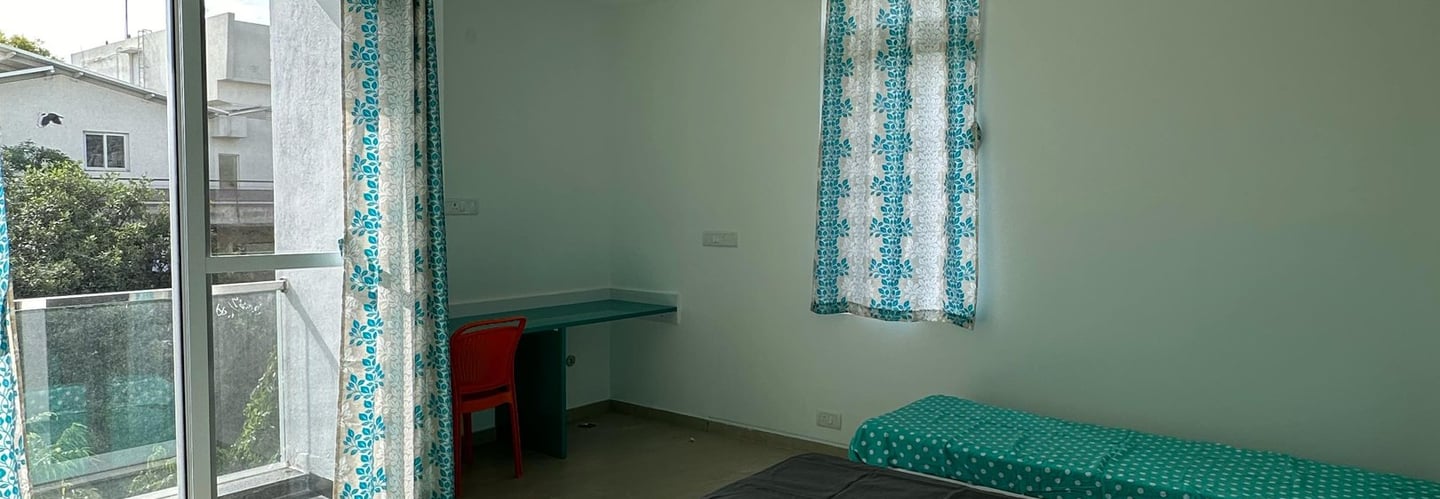 Spacious twin-sharing PG room in Banglore with a balcony, modern furniture, A/C and luxury.