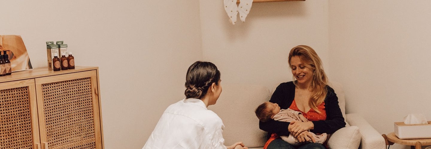 une femme qui se fait aider avec son bébé par une accompagnante périnatale