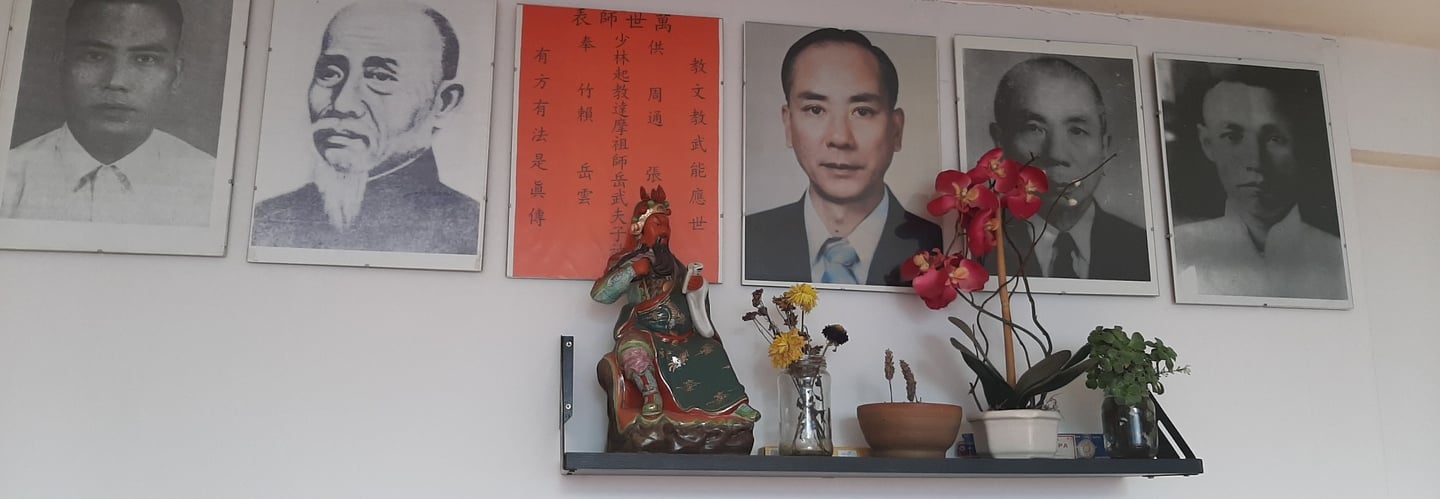 Altar de los maestros de kung fu. Una estatuilla de Guan Gong y pequeñas macetas con flores.