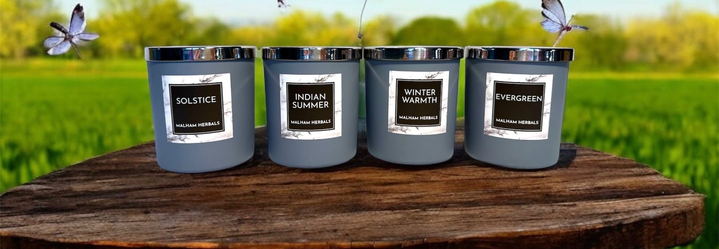 Four luxurious aromatherapy essential oil candles with a natural background