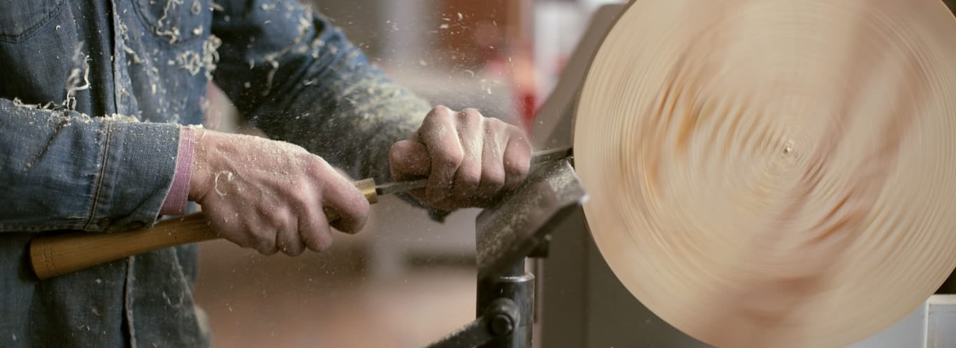 a person using a wood lather to make a large wooden bowl