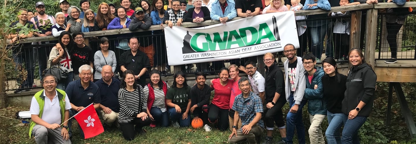 a group of people standing around a banner of GWADA