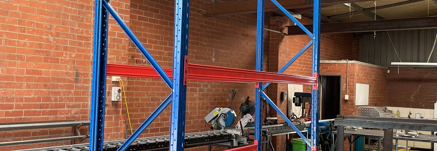 Heavy-duty steel pallet racking with assembled uprights and two solid shelves.