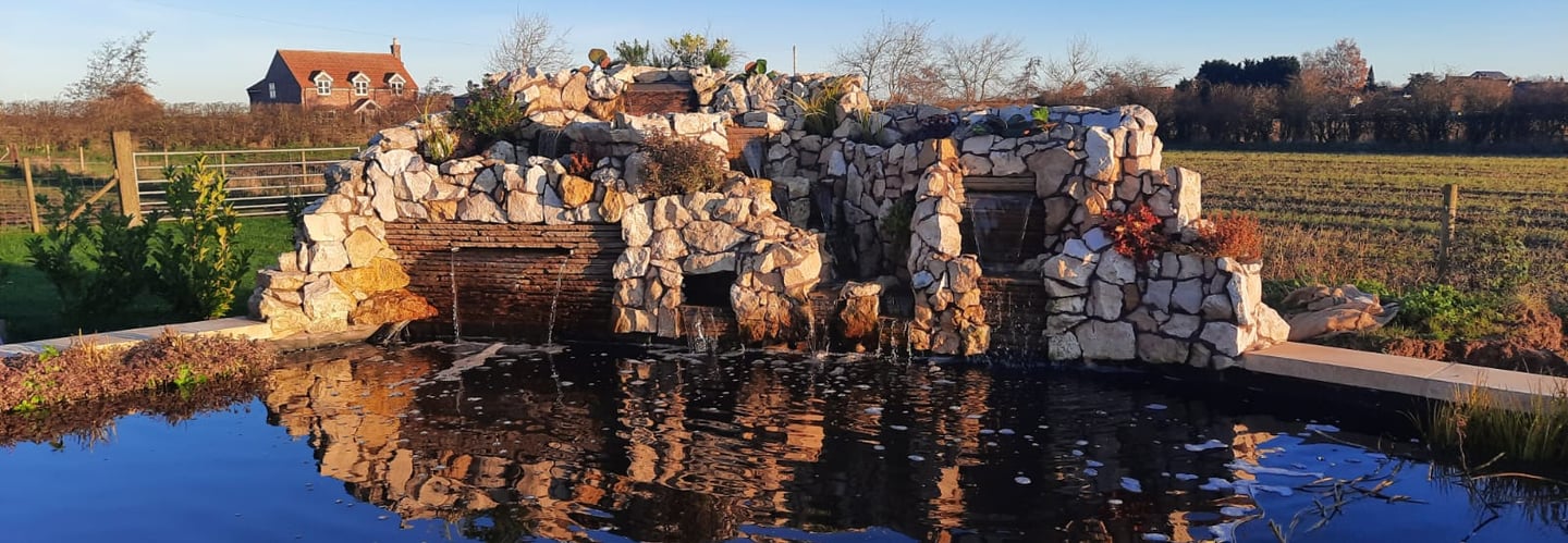 Custom corner water feature on a raised block ponds to bring the sound of running water