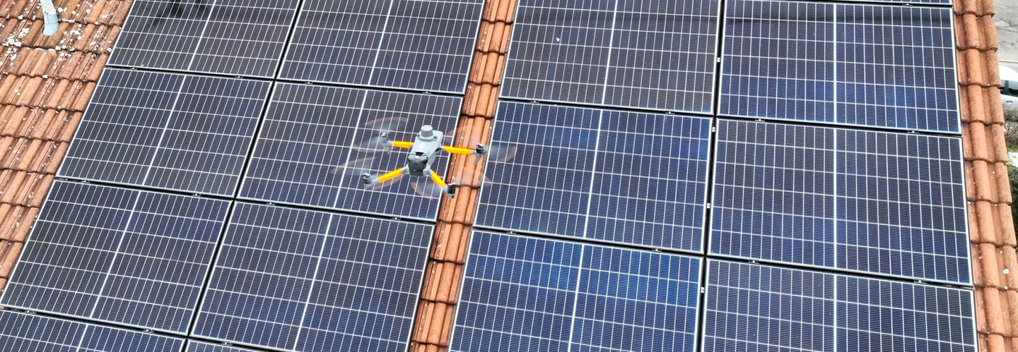 A thermal imaging drone performing an aerial inspection of residential rooftop solar panels.