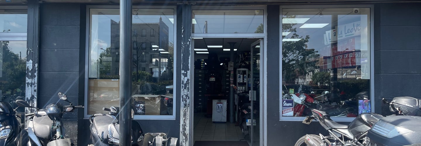 A Plaine Vitesse motorcycle shop storefront with scooters and motorbikes parked outside.