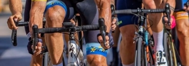 a group of cyclists riding bikes on a road