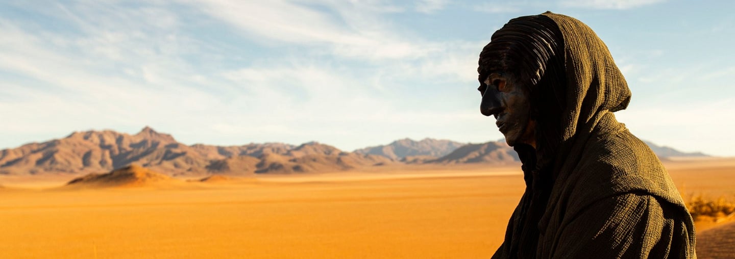 a man in a hoodedie standing in the desert