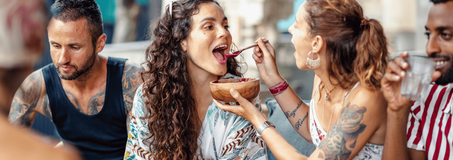 a woman eating a bowl of food while a man is eating