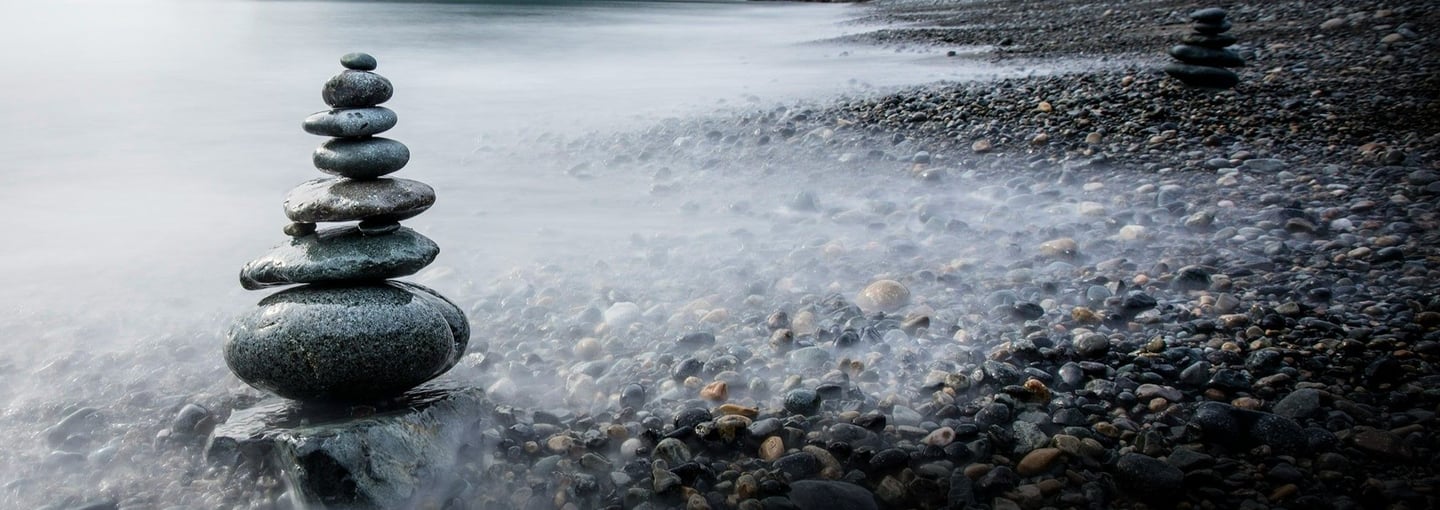 Cairn stones by the sea representing brave step towards healing and hope - Braver Days