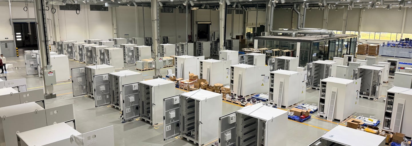 Wide view of an industrial manufacturing facility with rows of white electrical control cabinets.