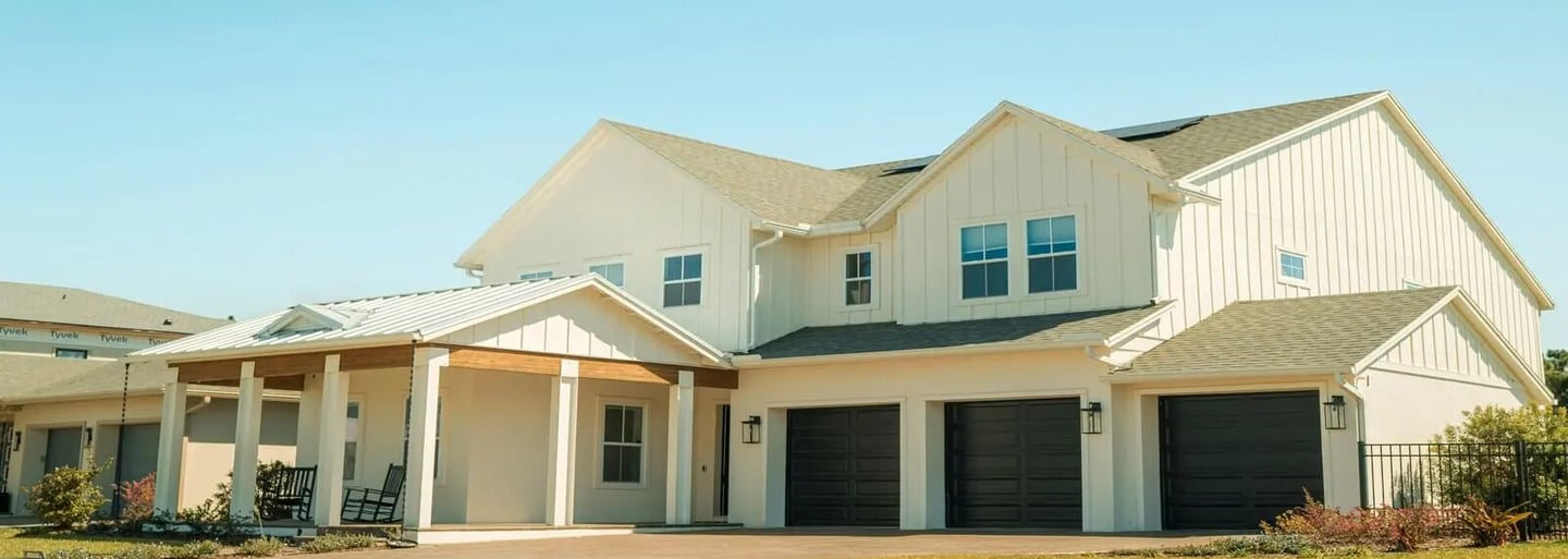 Modern residential house with large garage and landscaped front yard under a clear sky.