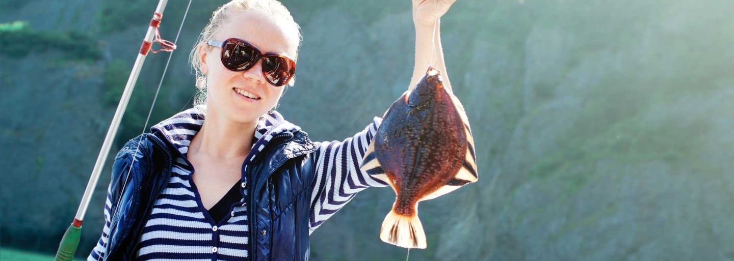 a woman holding a fish on a fishing boat