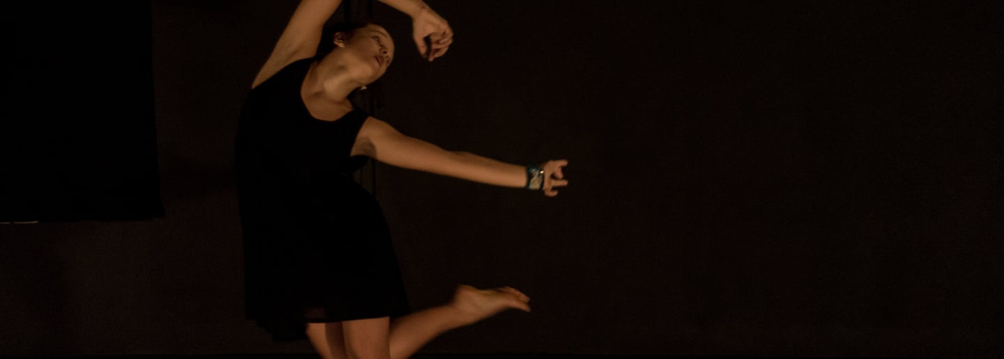 a woman in a black dress is dancing on stage
