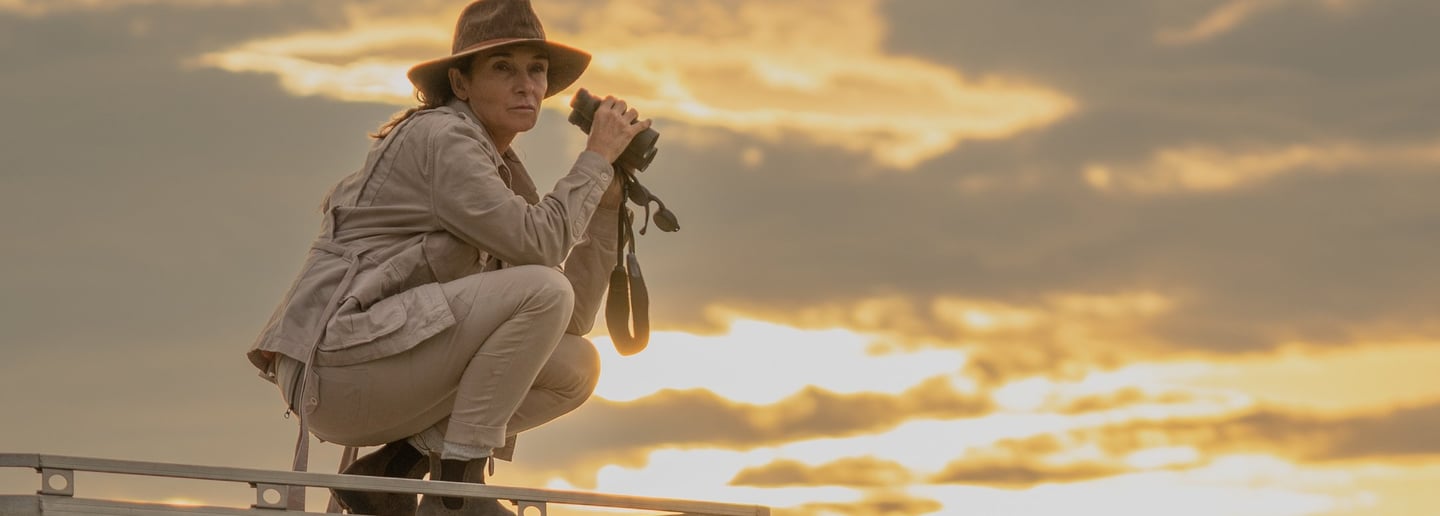 Woman with binoculars with dramatic sunset behind