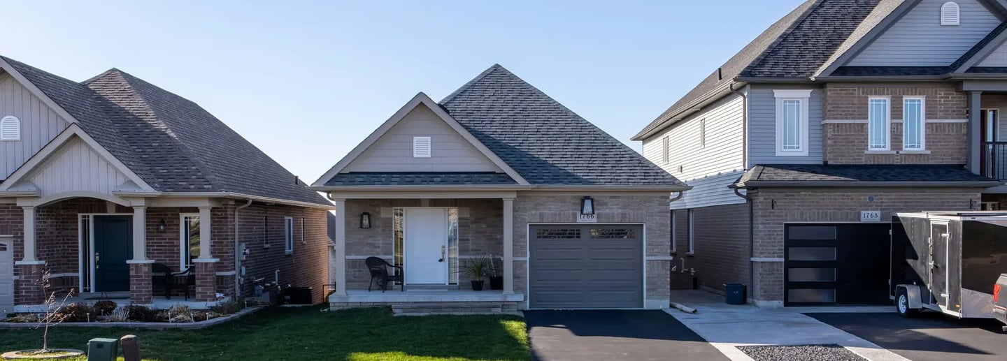 Front view of modern suburban houses with clean driveways and well-maintained lawns.