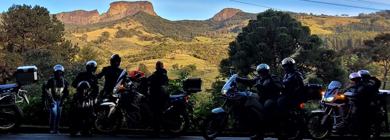 Pessoas de moto em frente à Pedra do Baú em São Bento do Sapucaí