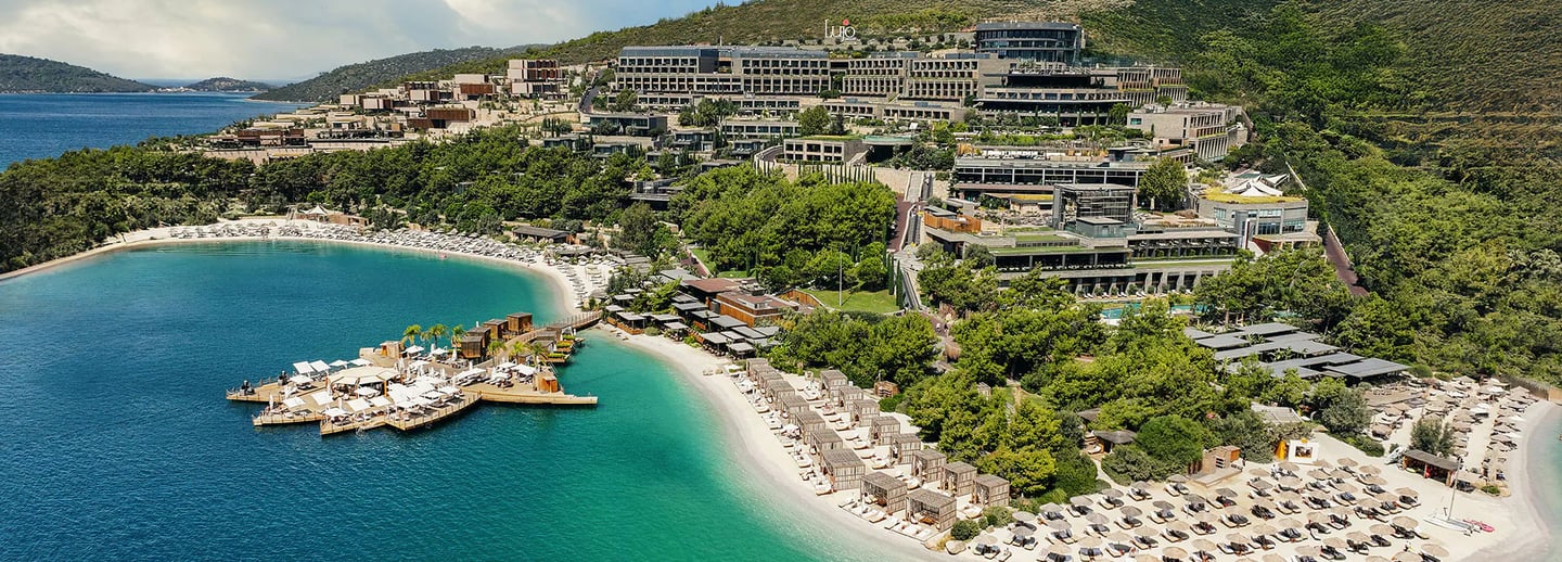 Aerial view of a luxury beachfront resort in Bodrum with turquoise water and sandy beaches.