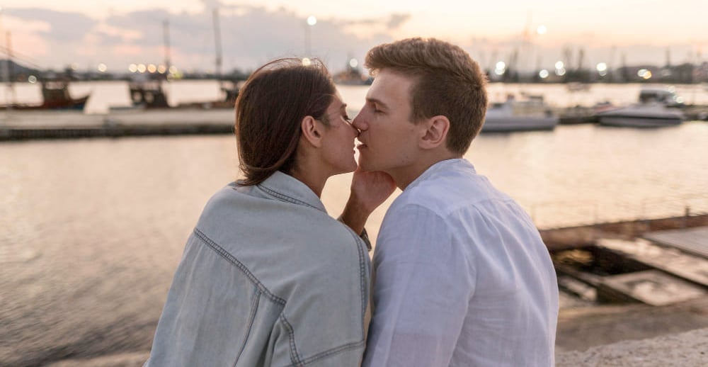 Sugar mommy and sugar baby sharing an intimate moment by the waterfront at dusk.