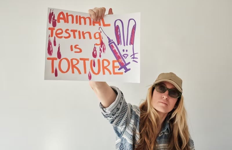 attivista che mostra scritto che fare test sugli animali è una tortura e conduce lotta la riforma dd