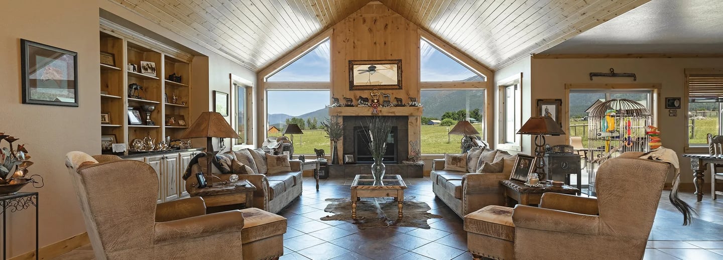 a living room with a fireplace and large windows with Montana mountains outside
