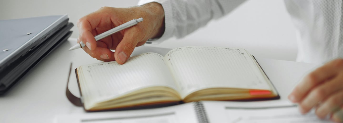 Mężczyzna przewracający kartki w kalendarzu. Zachęta potencjalnego klienta do kontaktu.