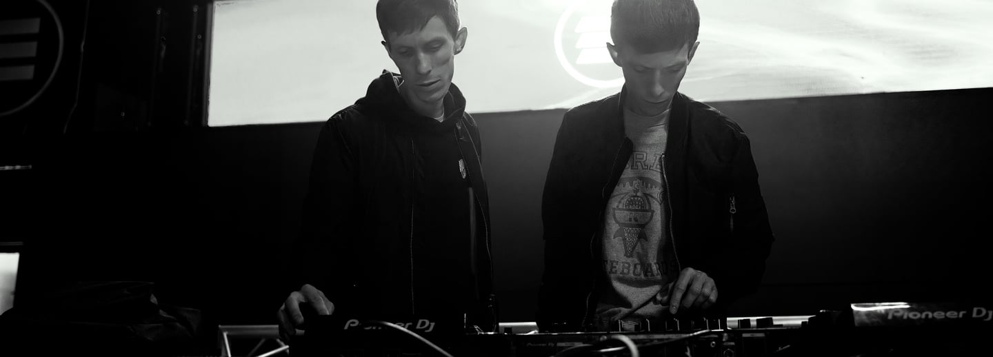 Twins brothers standing in front of a stage with a large screen