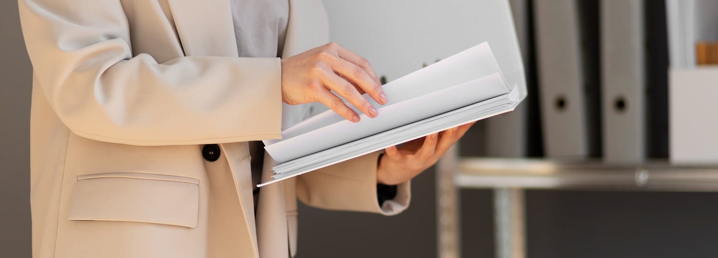 a woman in a business suit is holding a laptop