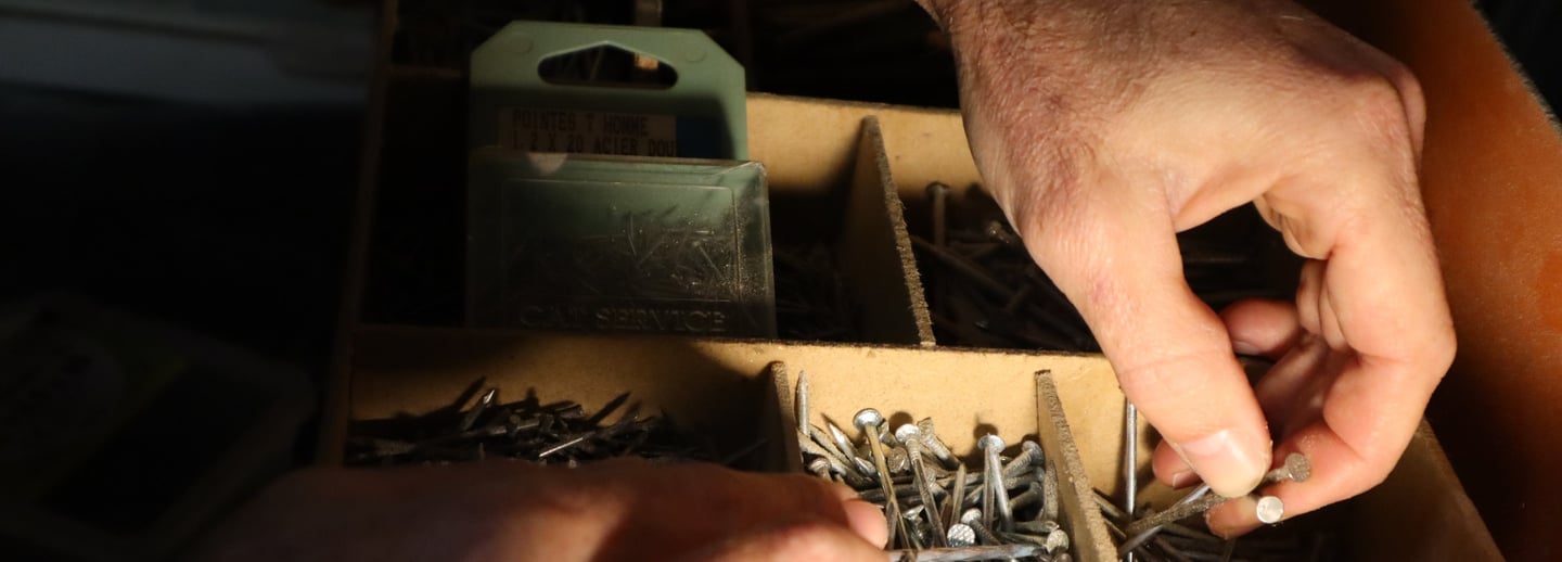 artisan qui prend des pointes dans son atelier pour faire de la charpente