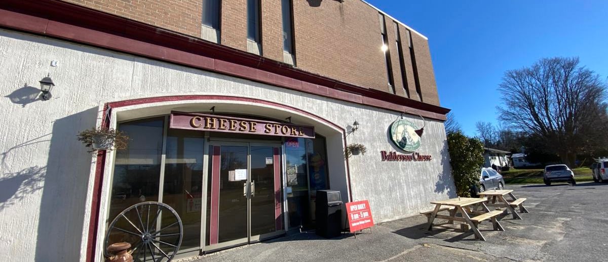 Exterior view of the Balderson Cheese Store storefront with outdoor picnic tables and rustic decor.