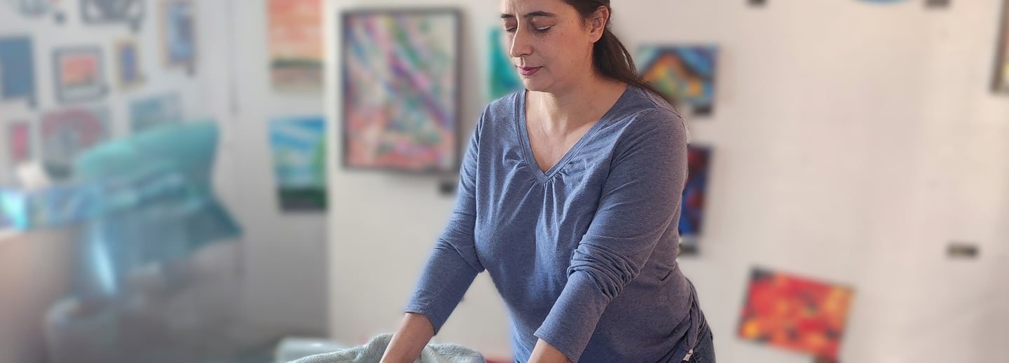 Professional female Reiki therapist arranging blankets in a relaxing art-filled therapy room.