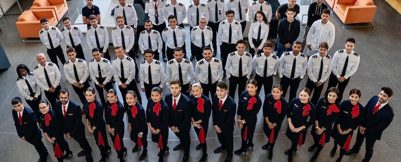Diverse group of aviation students in uniforms reviewing flight plans in a classroom