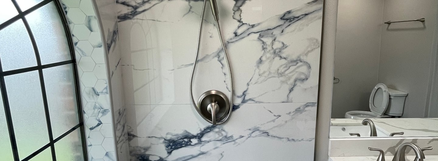Modern bathroom featuring marble-patterned wall tiles, a rainfall showerhead, and a matching hexagon floor.