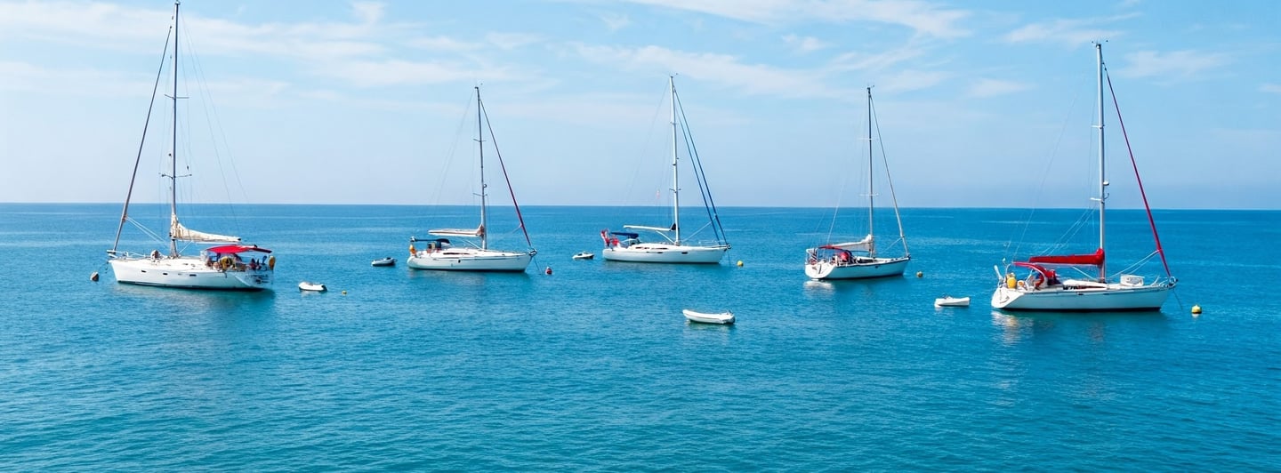 Voiliers blancs au mouillage, mer translucide et ciel bleu