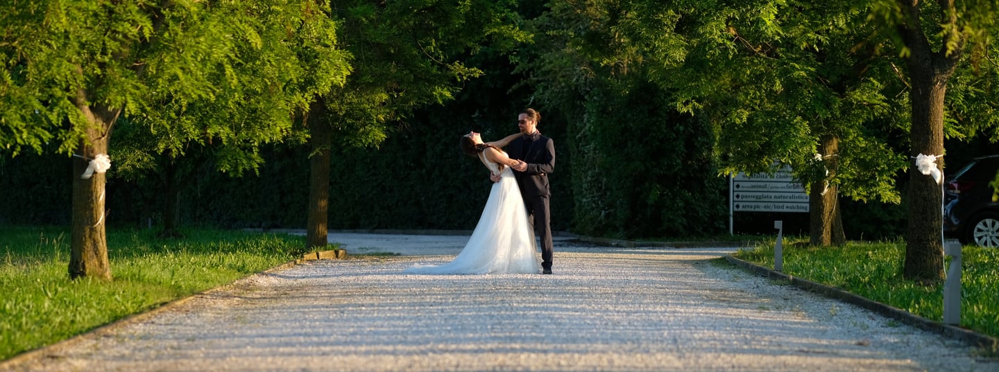 a bride and groom are standing in a park