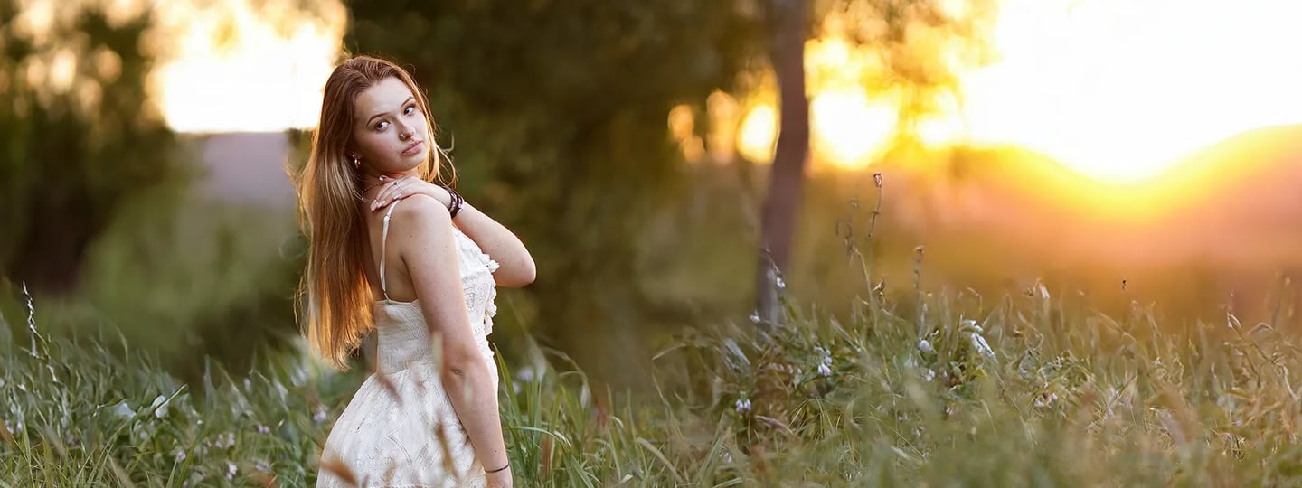 une jeune femme pose pour une séance photo au soleil couchant