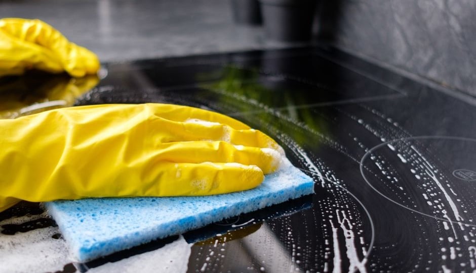 Cleaner cleaning a counter top with yellow gloves and a blue sponge