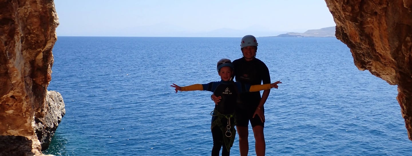 Manue et Leonie debout sous l'arche de la grotte avec la mer en fond