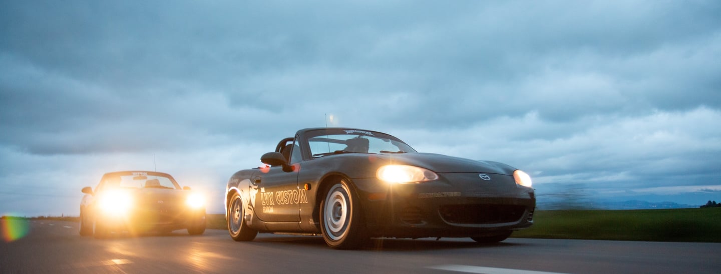 two cars driving on a highway with headlights on
