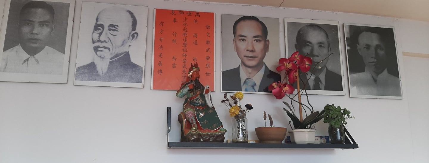 Altar de los maestros de kung fu. Una estatuilla de Guan Gong y pequeñas macetas con flores.