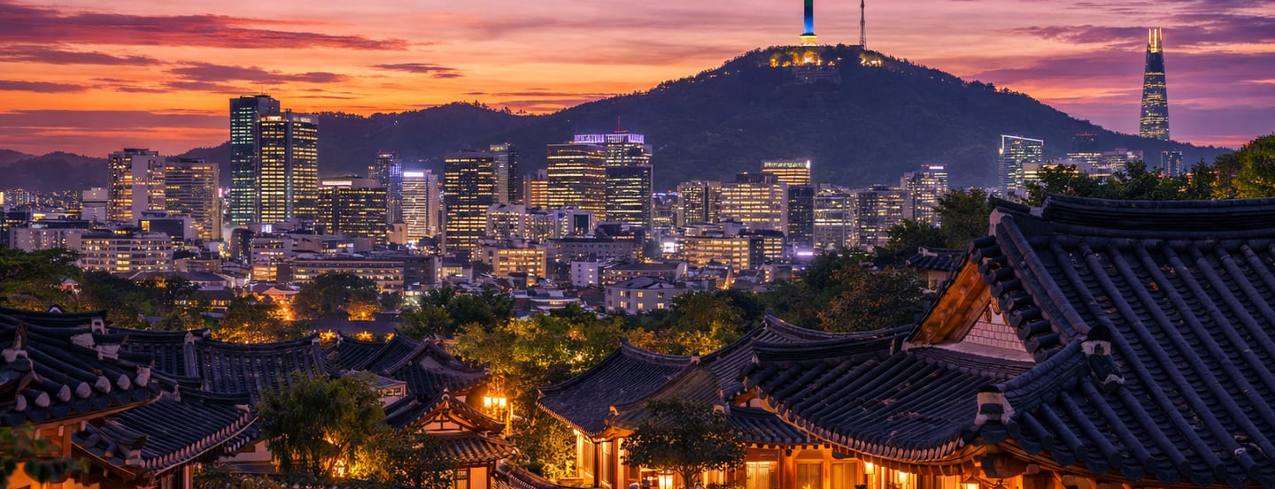 The image shows a beautiful sunset view of Seoul with traditional hanok houses in the foreground and