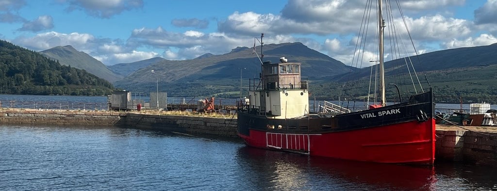 a boat docked at a pier with hills in the background