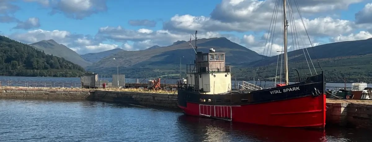 a boat docked at a pier with hills in the background