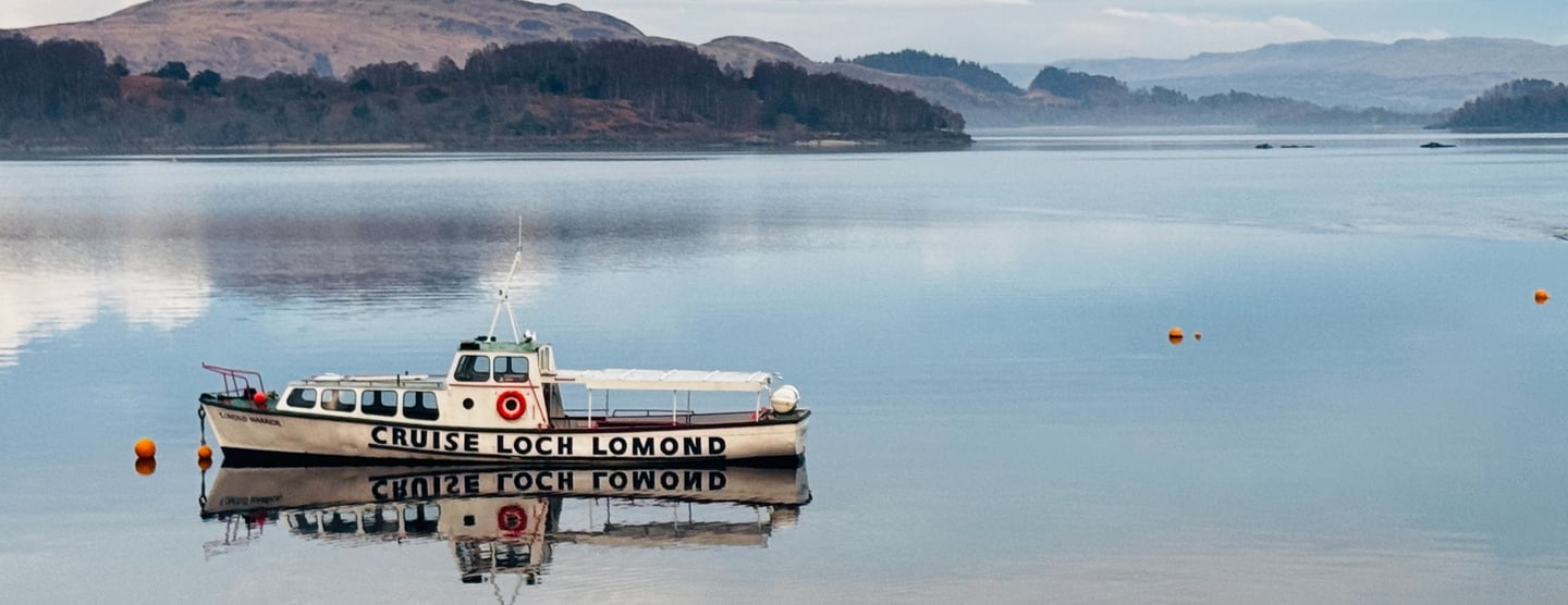 a boat in the water will hills in the background