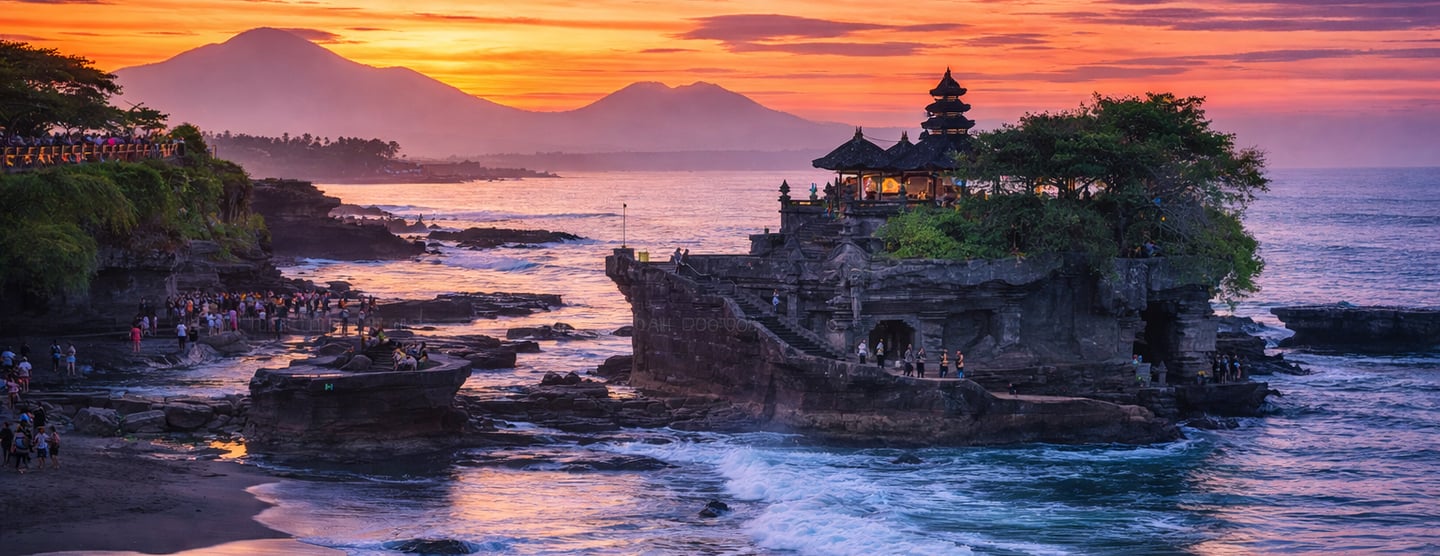 This image shows a dramatic sunset view of Tanah Lot temple in Bali with ocean waves, glowing sky, a