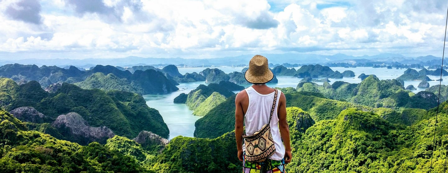 a man standing on a mountain top with a hat on