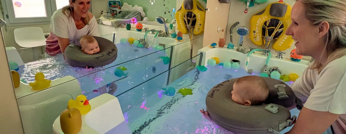 baby qui se regarde dans son bain et une bouée de cou à travers un grand miroir