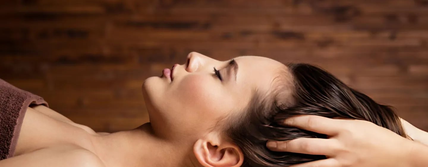 A woman receiving a relaxing professional head massage at a luxury wellness spa package resort.