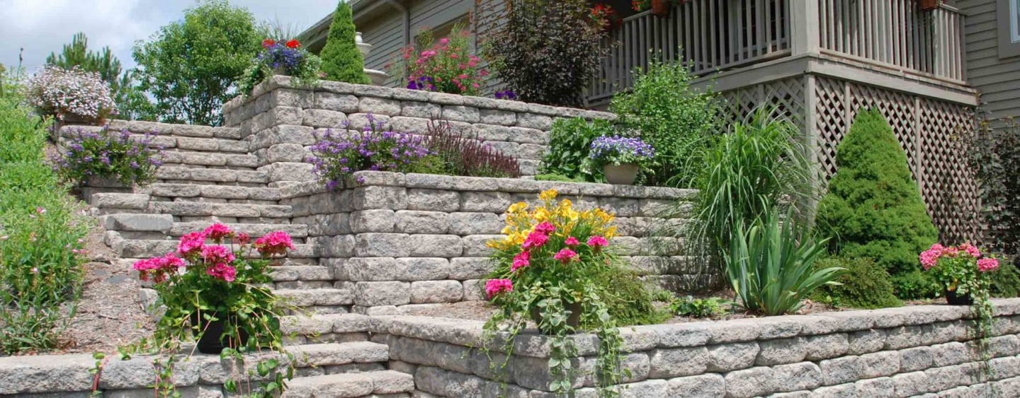 Landscaped block retaining wall with stone steps and plants
